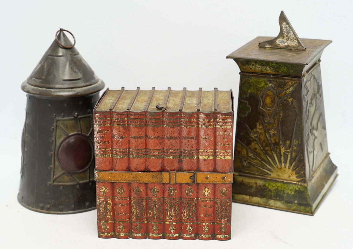 Three early 20th century Huntley & Palmer novelty biscuit tins, modelled as bound books, a sun dial and an Arts & Crafts lantern, largest 24cm high. Condition - fair